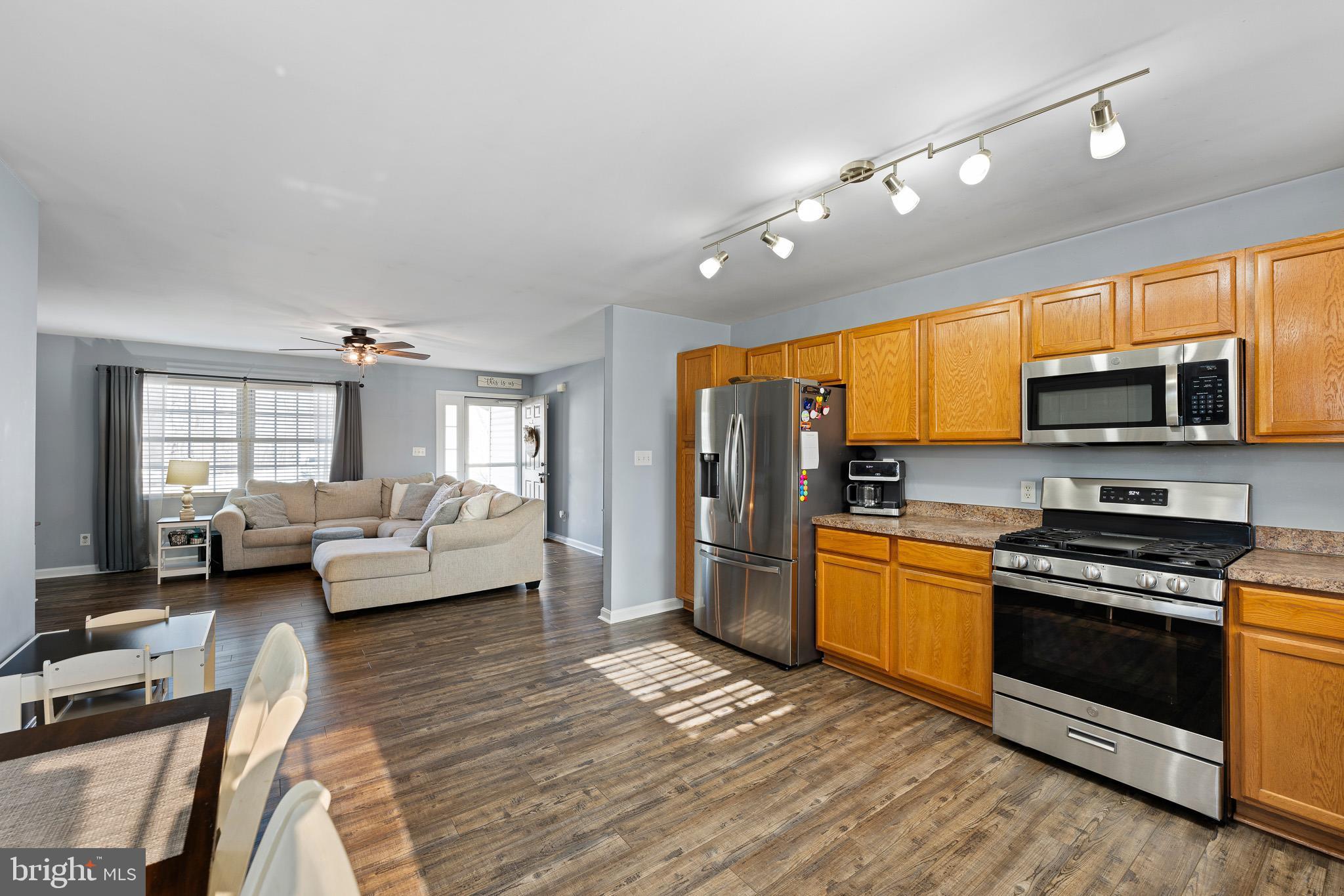 70 West Deer Trail Road Clayton, DE 19938 - Photo 11 of 25 a kitchen with stainless steel appliances granite countertop a stove top oven a sink dishwasher a dining table and chairs with wooden floor