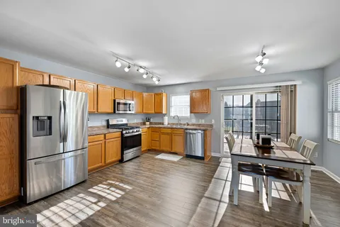 a kitchen with stainless steel appliances granite countertop a refrigerator a sink dishwasher stove and oven with wooden floor