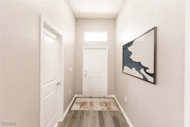 a view of a hallway with wooden floor and a bathroom