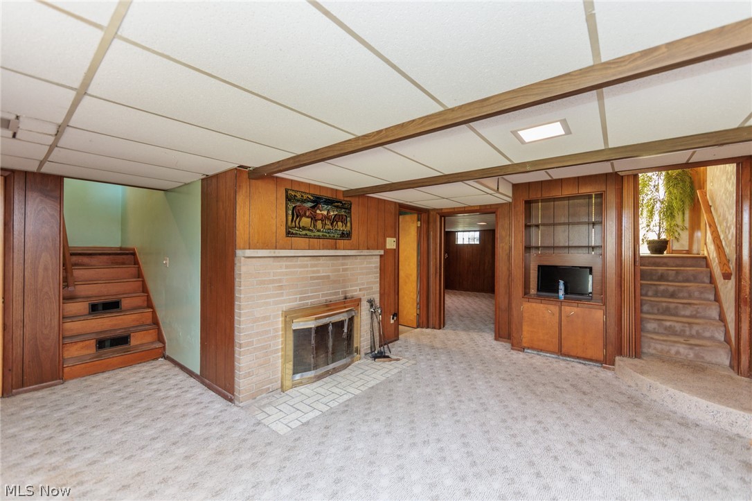 2170 Norton Road Stow, OH 44224 - Photo 43 of 48 Lower level living area featuring a light-colored carpet, a fireplace with a light brick surround, and wood-paneled walls