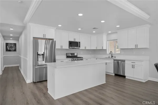 a kitchen with stainless steel appliances granite countertop a refrigerator a stove top oven a sink and dishwasher with wooden floor