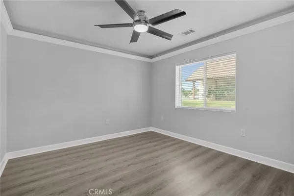 an empty room with wooden floor ceiling fan and windows
