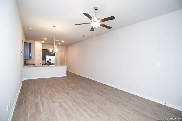 a view of an empty room with wooden floor and a chandelier