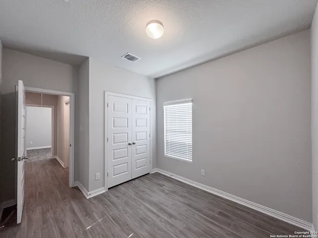 an empty room with wooden floor closet and windows