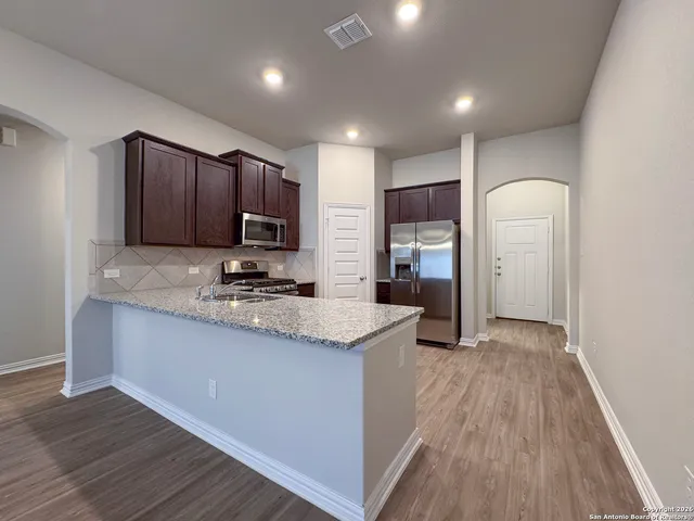 a kitchen with granite countertop wooden cabinets and stainless steel appliances