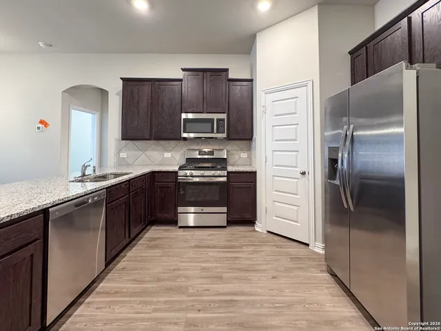a large kitchen with wooden floors and stainless steel appliances