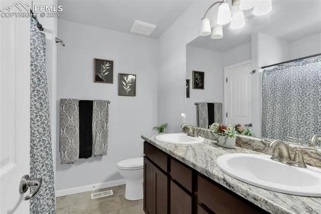 a bathroom with a granite countertop sink a toilet and a mirror