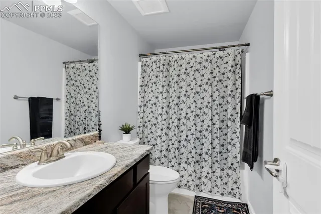 a bathroom with a granite countertop sink a toilet and a mirror
