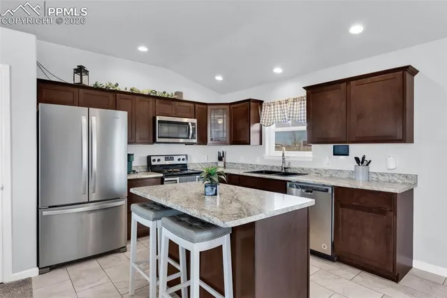 a kitchen with stainless steel appliances granite countertop a sink a stove a refrigerator and a microwave