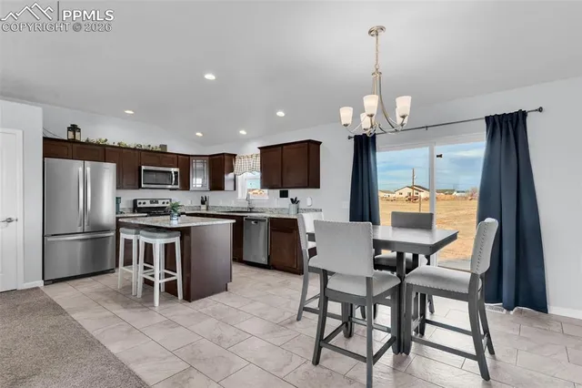 a kitchen with stainless steel appliances kitchen island granite countertop a table chairs microwave and refrigerator