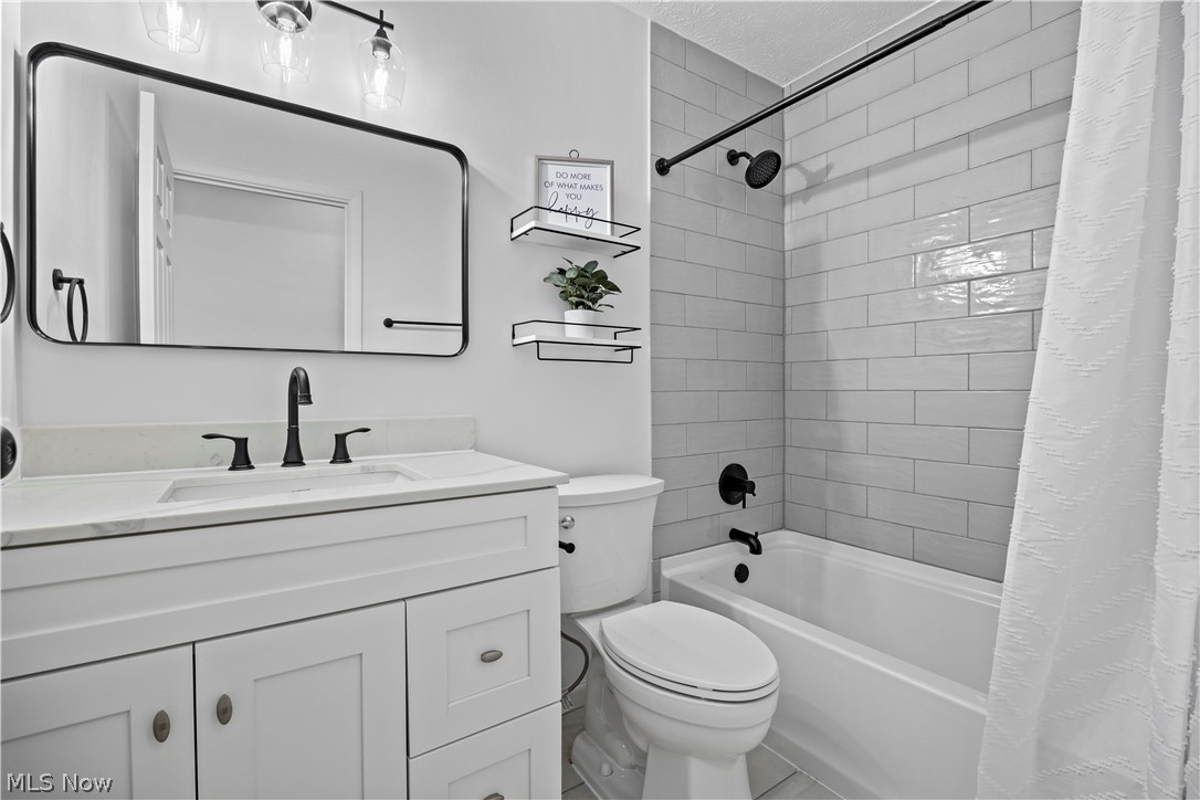 32969 Mills Road North Ridgeville, OH 44039 - Photo 20 of 29 Full bathroom featuring oversized vanity, toilet, tile flooring, shower / tub combo with curtain, and a textured ceiling