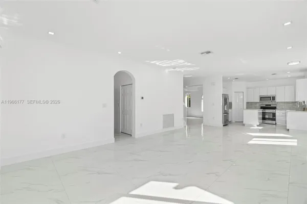 a view of kitchen with refrigerator and white cabinets