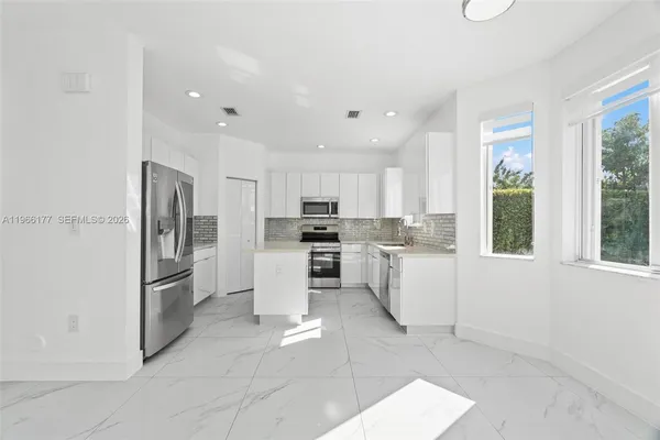a kitchen with white cabinets and stainless steel appliances