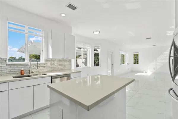 a kitchen with stainless steel appliances granite countertop a sink and dishwasher with white cabinets