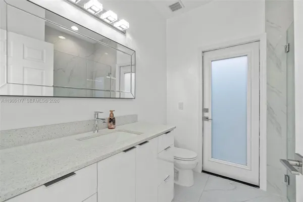 a bathroom with a toilet a sink a light fixture and a mirror