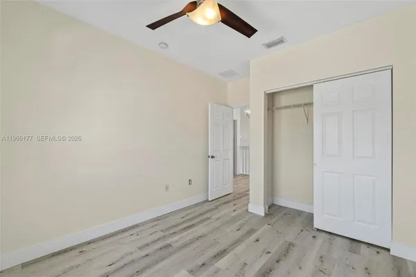 an empty room with wooden floor and a ceiling fan