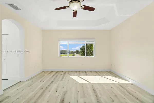 an empty room with wooden floor fan and windows