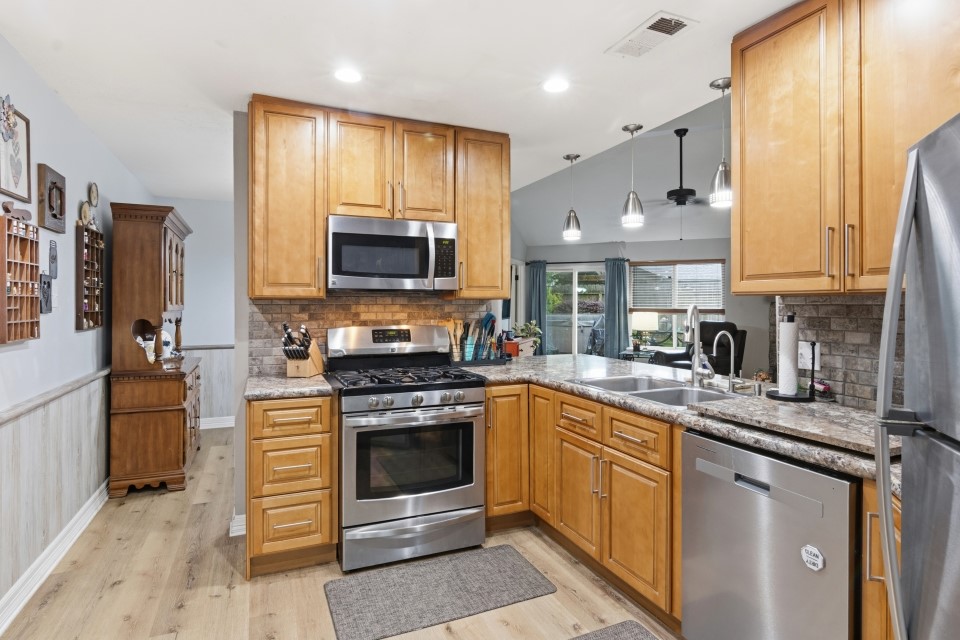 9211 Benwick Street Spring, TX 77379 - Photo 12 of 27 a kitchen with stainless steel appliances granite countertop a stove top oven a sink dishwasher a refrigerator and a microwave