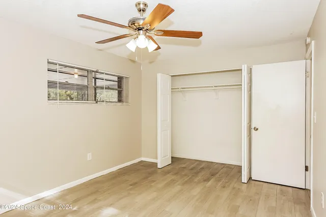 an empty room with a chandelier fan and windows