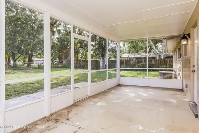 a view of an empty room with wooden floor and a large window