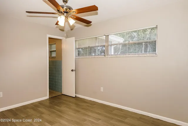 an empty room with a window and a fan