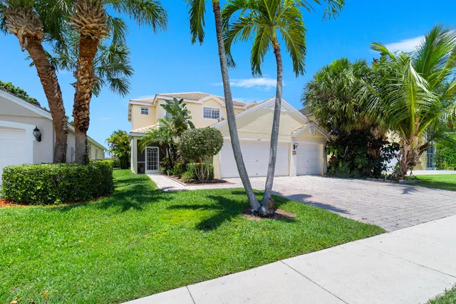 a view of a house with a yard and palm trees