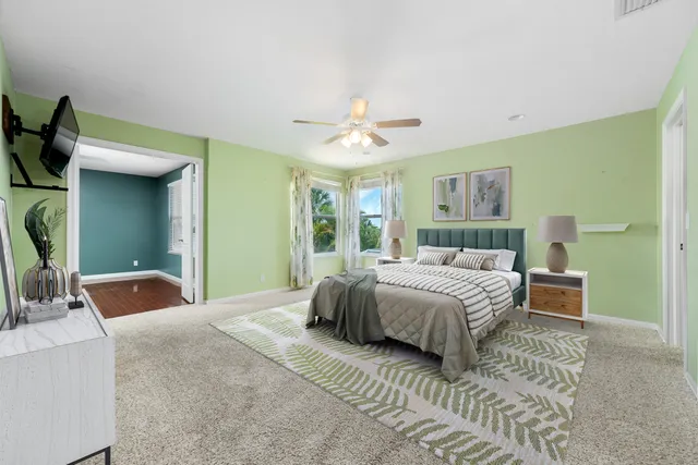 an empty room with wooden floor fan and windows