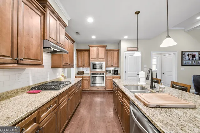 a kitchen with kitchen island granite countertop a sink a counter space appliances and cabinets