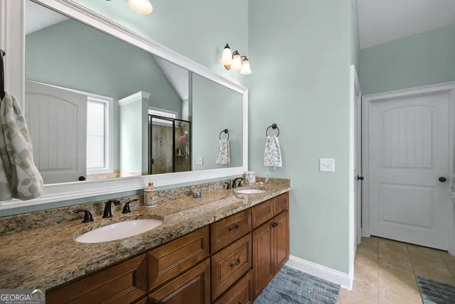 a bathroom with a granite countertop double vanity sink and a mirror