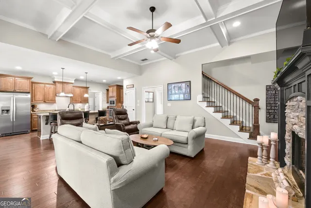 a living room with furniture kitchen view and a wooden floor