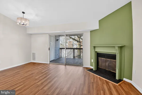 an empty room with wooden floor fireplace and windows