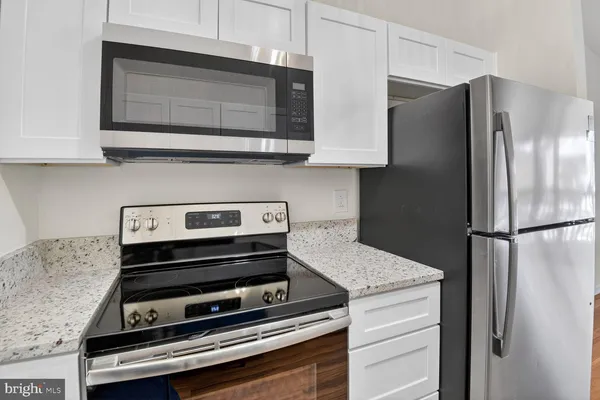 a kitchen with granite countertop a refrigerator stove and microwave