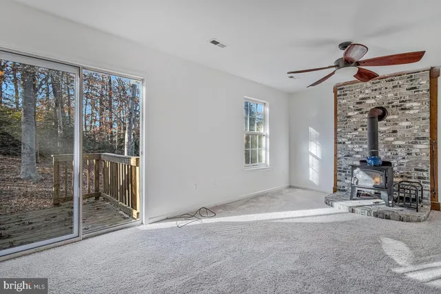 an empty room with staircase and ceiling fan