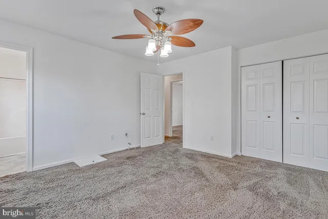 an empty room with closet and a chandelier fan