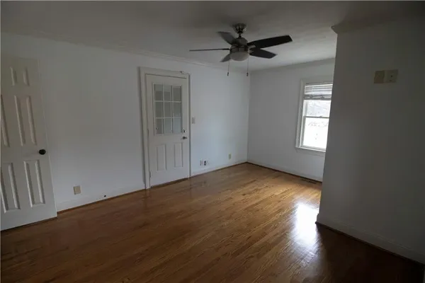 an empty room with wooden floor and windows