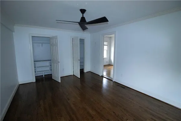 a view of empty room with wooden floor and ceiling fan