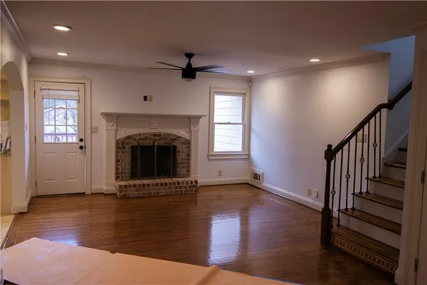 a view of an empty room with wooden floor fireplace and a window