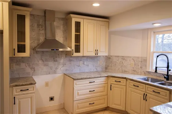 a kitchen with granite countertop a sink a stove and cabinets