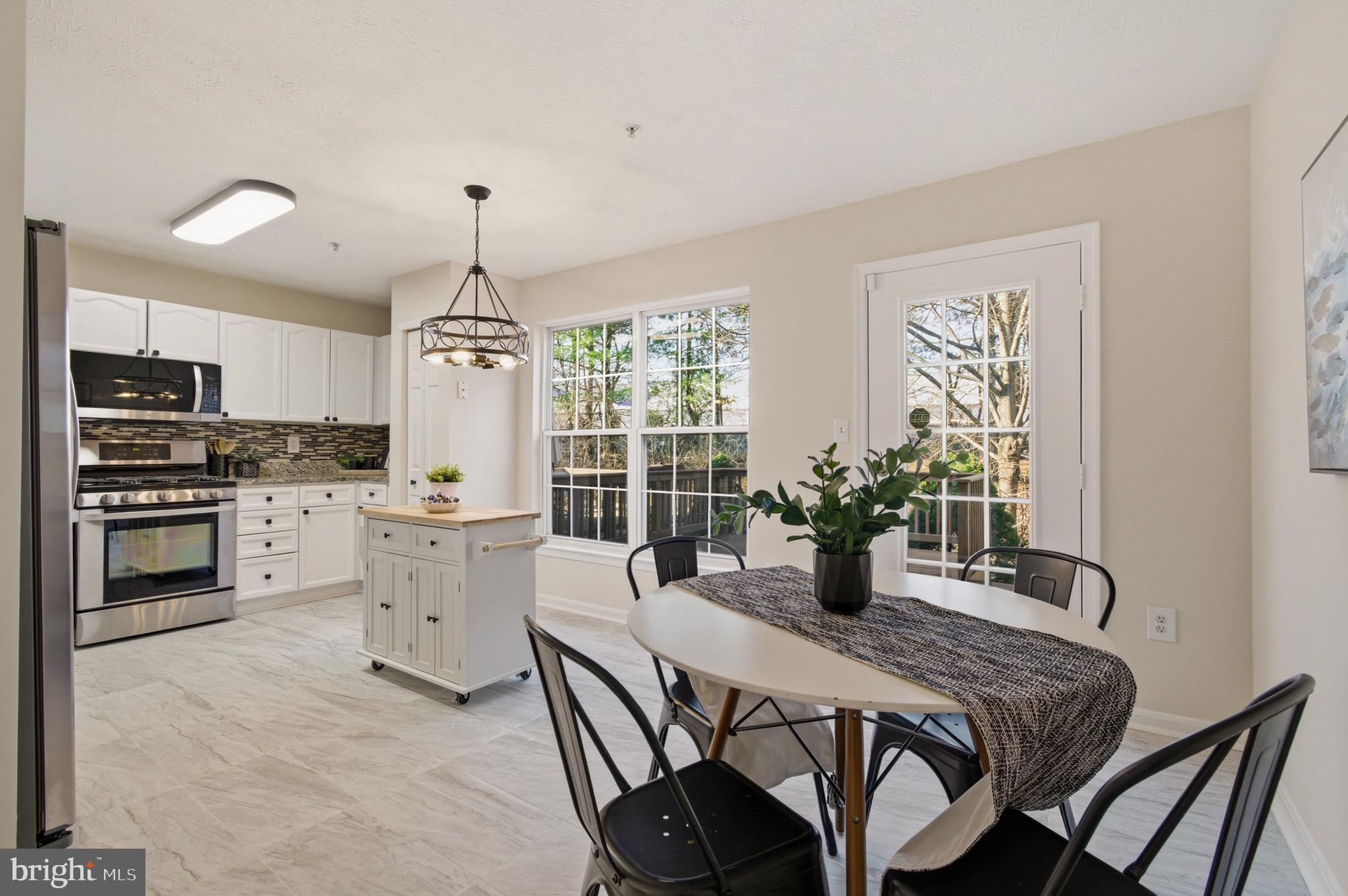 9054 Constant Course Columbia, MD 21046 - Photo 25 of 61 a kitchen with stainless steel appliances kitchen island granite countertop a stove a sink dishwasher a dining table and chairs with wooden floor