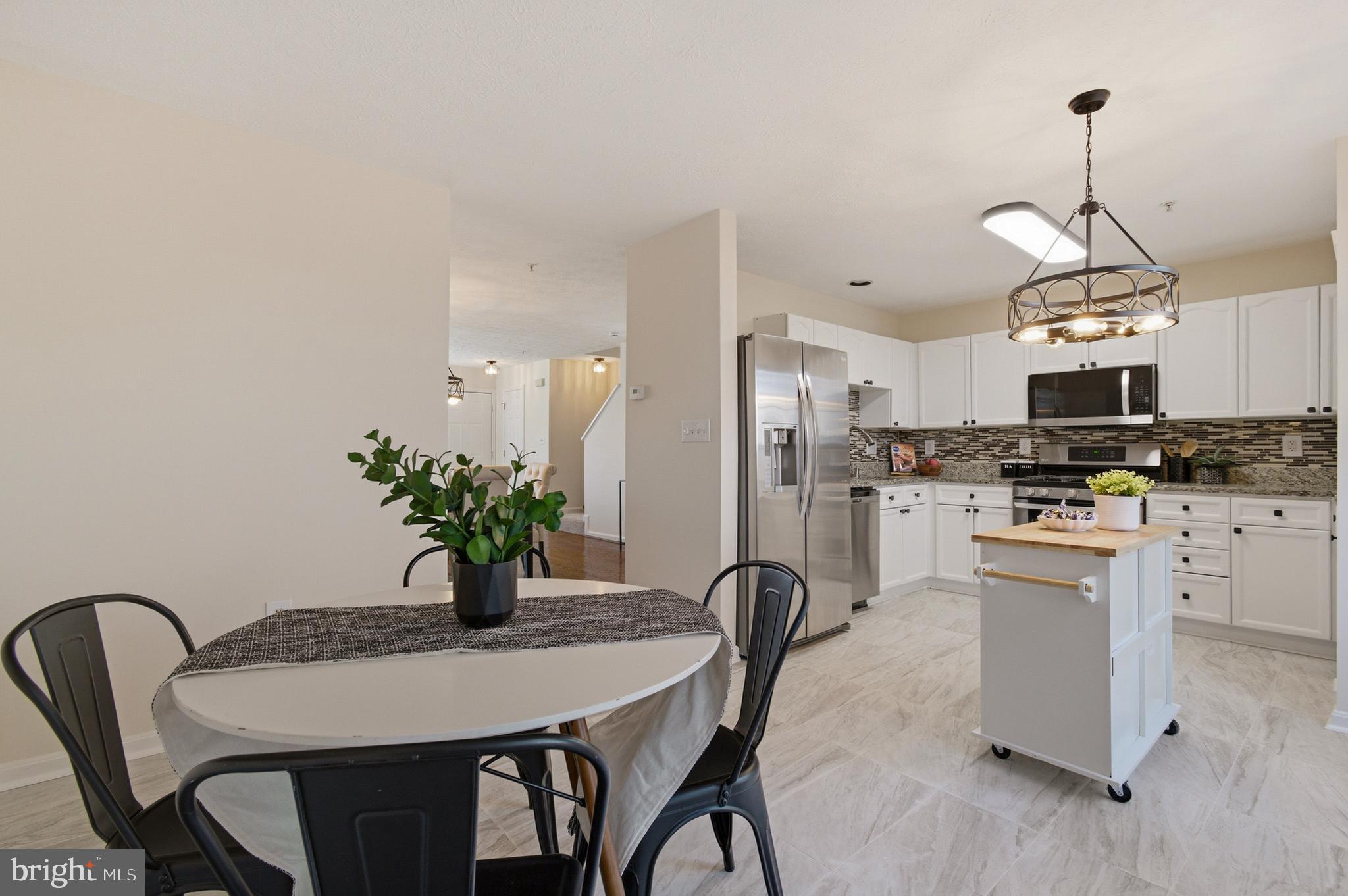 9054 Constant Course Columbia, MD 21046 - Photo 26 of 61 a kitchen with stainless steel appliances kitchen island granite countertop a dining table chairs and white cabinets