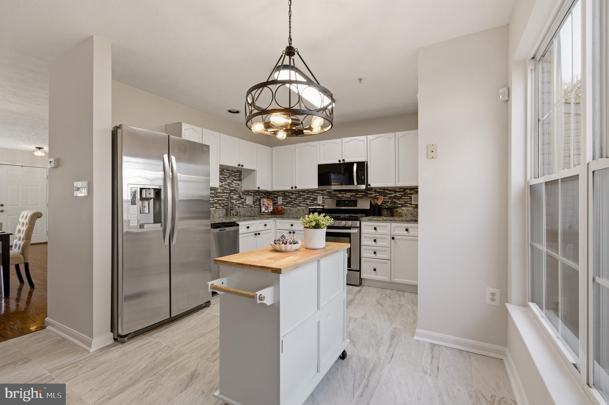 9054 Constant Course Columbia, MD 21046 - Photo 28 of 61 a kitchen with stainless steel appliances granite countertop a refrigerator a stove microwave and a sink with wooden floor