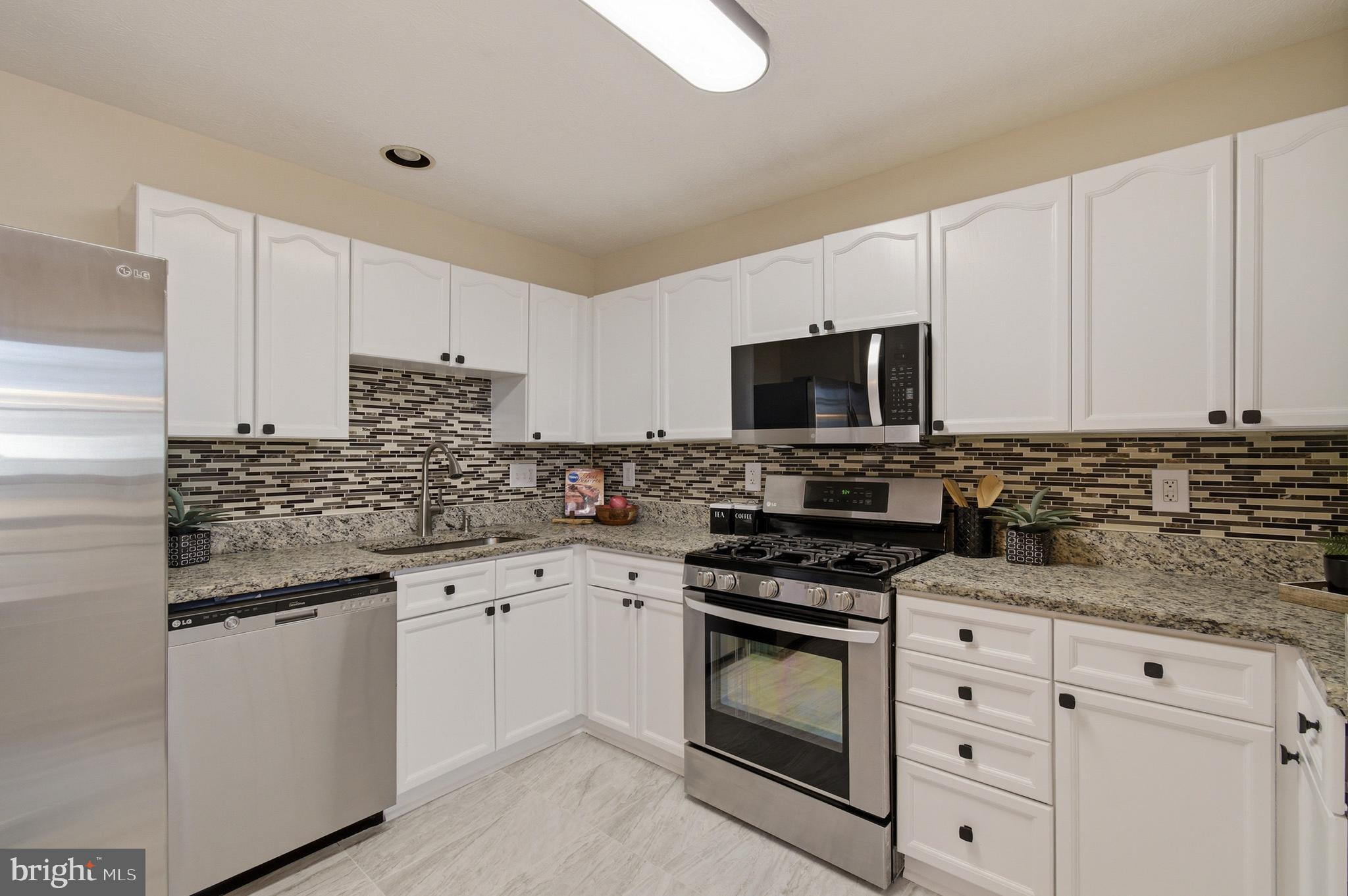 9054 Constant Course Columbia, MD 21046 - Photo 31 of 61 a kitchen with granite countertop white cabinets white stainless steel appliances and a sink