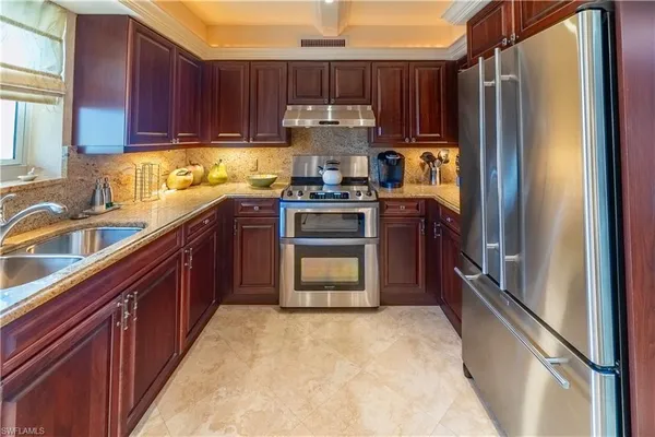 a kitchen with kitchen island granite countertop wooden cabinets stainless steel appliances a sink and a window