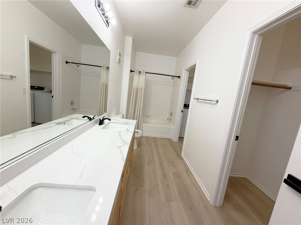8725 West Flamingo Road, Unit 226 Las Vegas, NV 89147 - Photo 3 of 11 Bathroom with a spacious closet, double vanity, shower / tub combo with curtain, and light wood-style floors