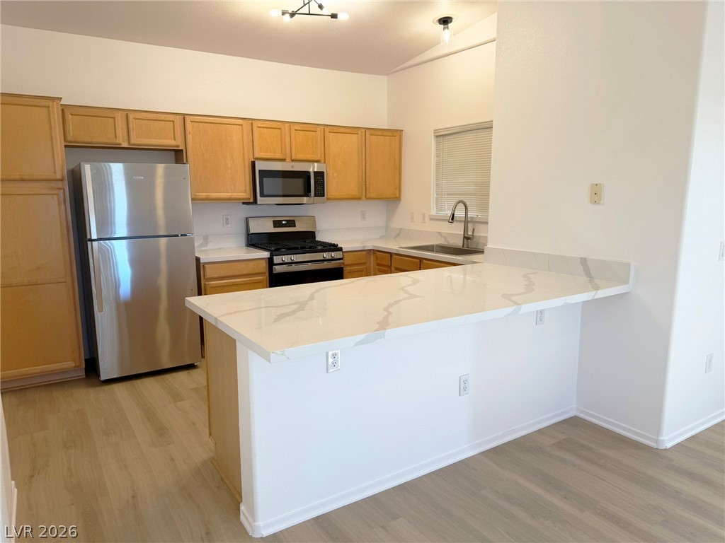 8725 West Flamingo Road, Unit 226 Las Vegas, NV 89147 - Photo 10 of 11 Kitchen featuring stainless steel appliances, a peninsula, light wood-style flooring, and light stone counters