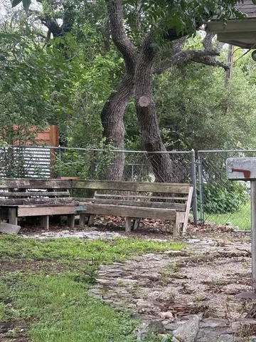 a view of a backyard with a wooden bench plants