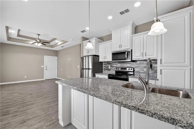 a kitchen with granite countertop a sink stainless steel appliances and a counter top space