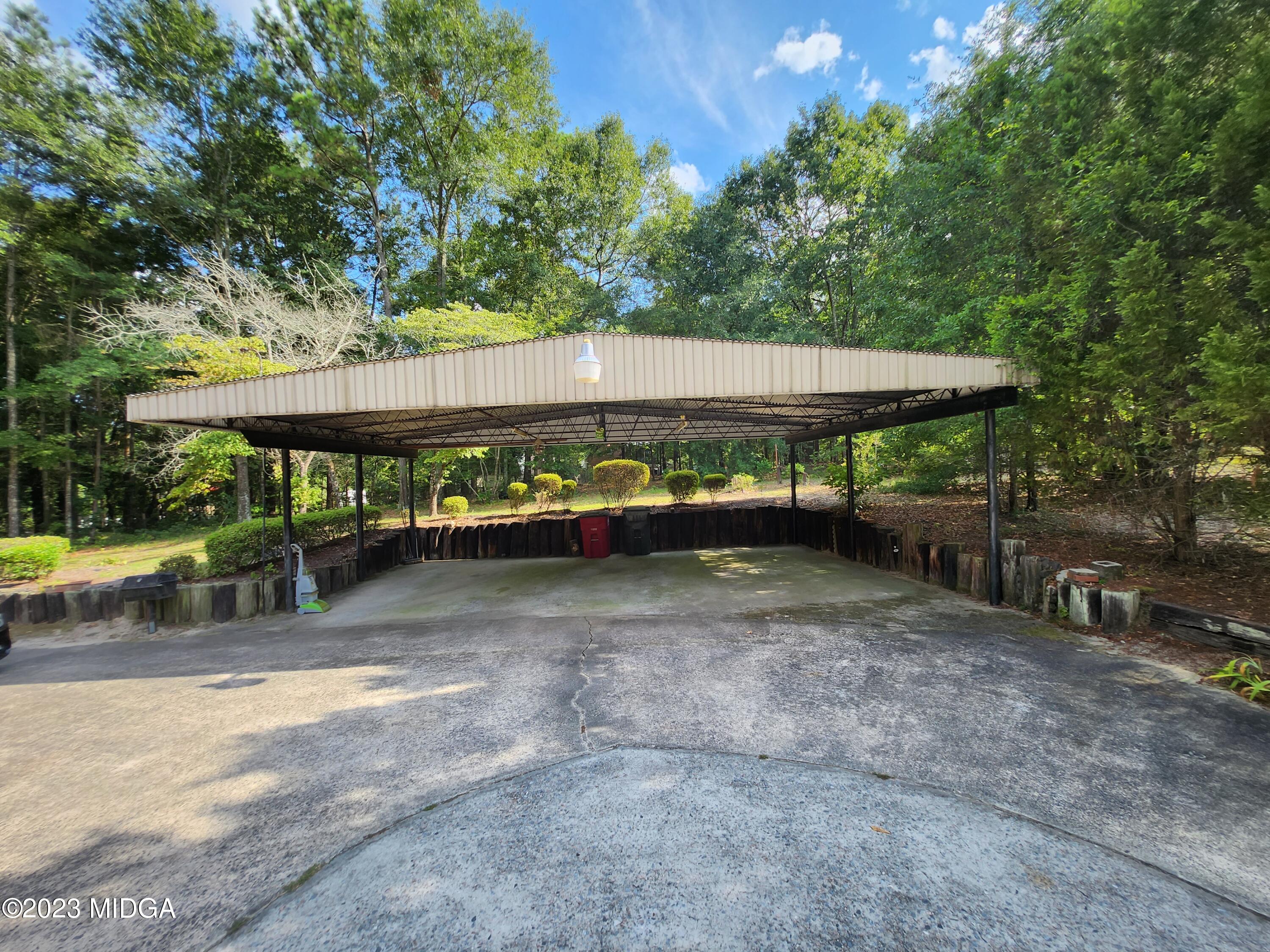7338 Columbus Road Lizella, GA 31052 - Photo 9 of 33 a view of a patio with table and chairs under an umbrella with large trees