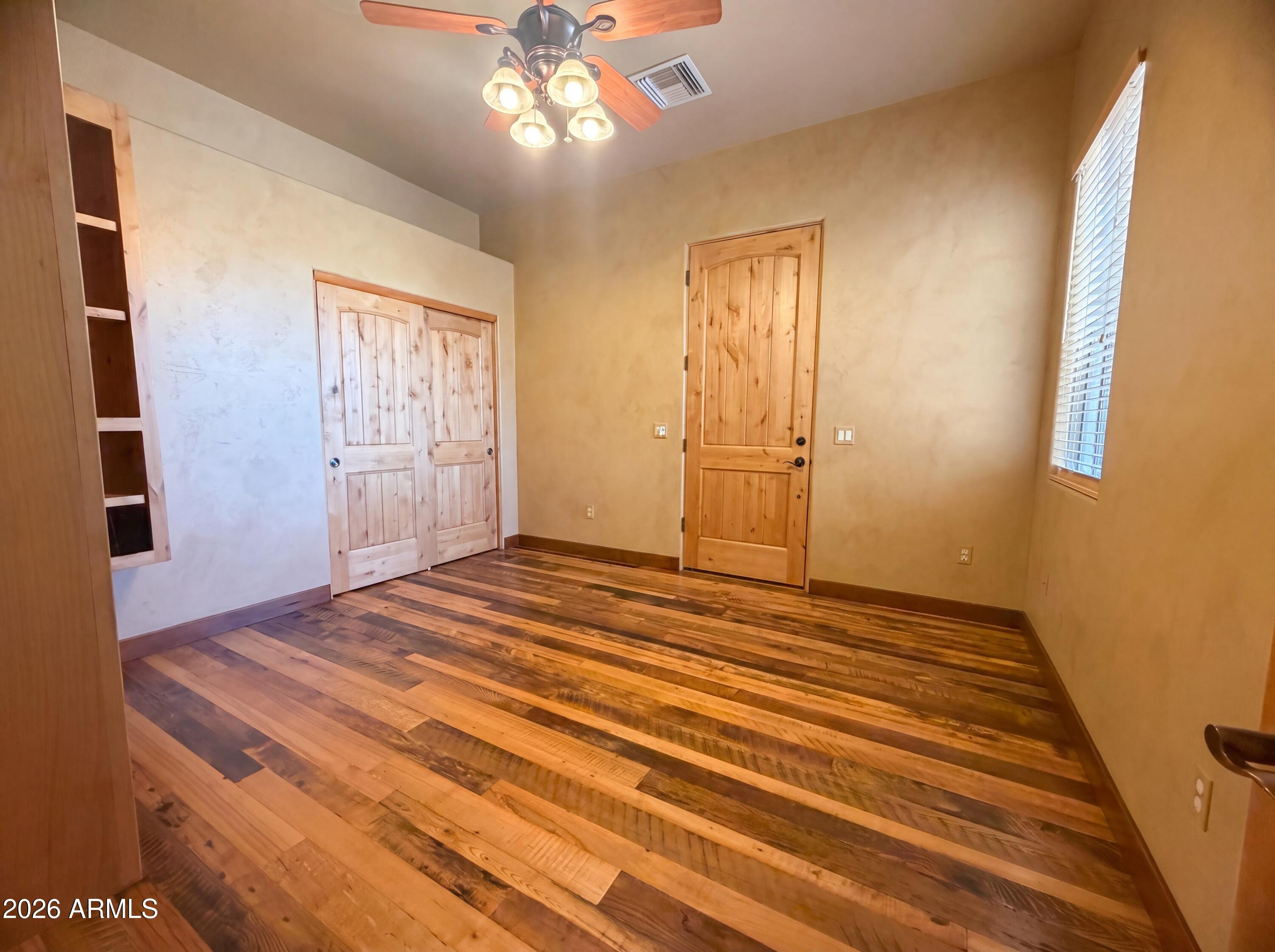 4496 South Kings Ranch Road Gold Canyon, AZ 85118 - Photo 13 of 22 a view of empty room with wooden floor and fan