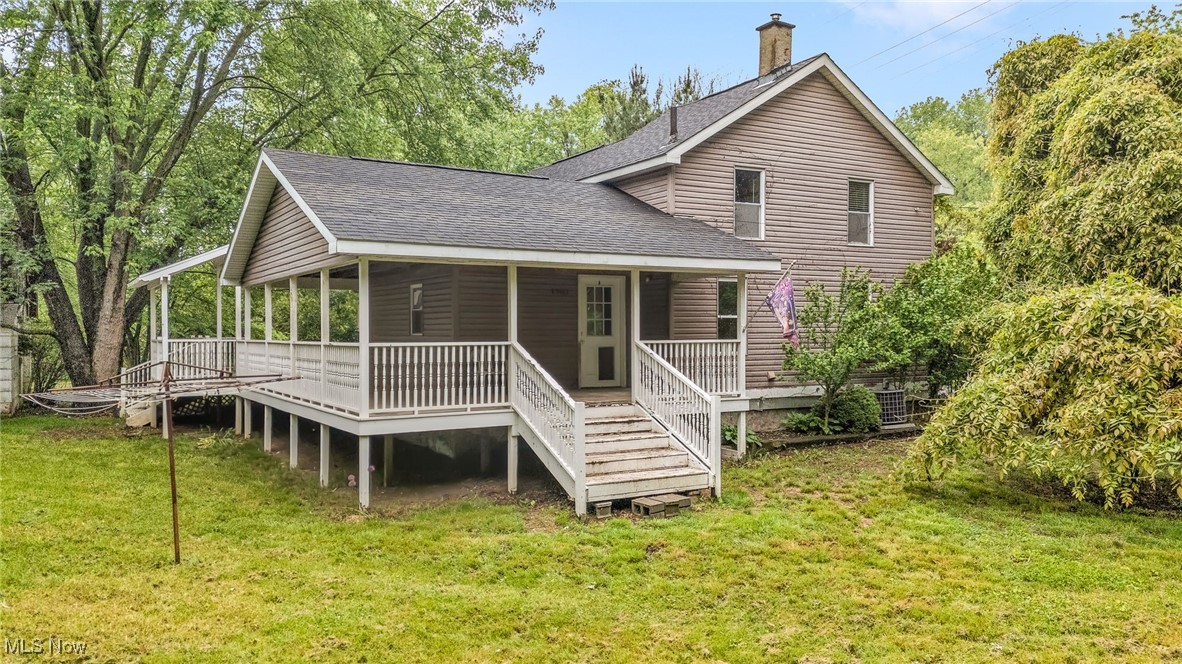 Rear view of house with a shingled roof, a chimney, and a yard